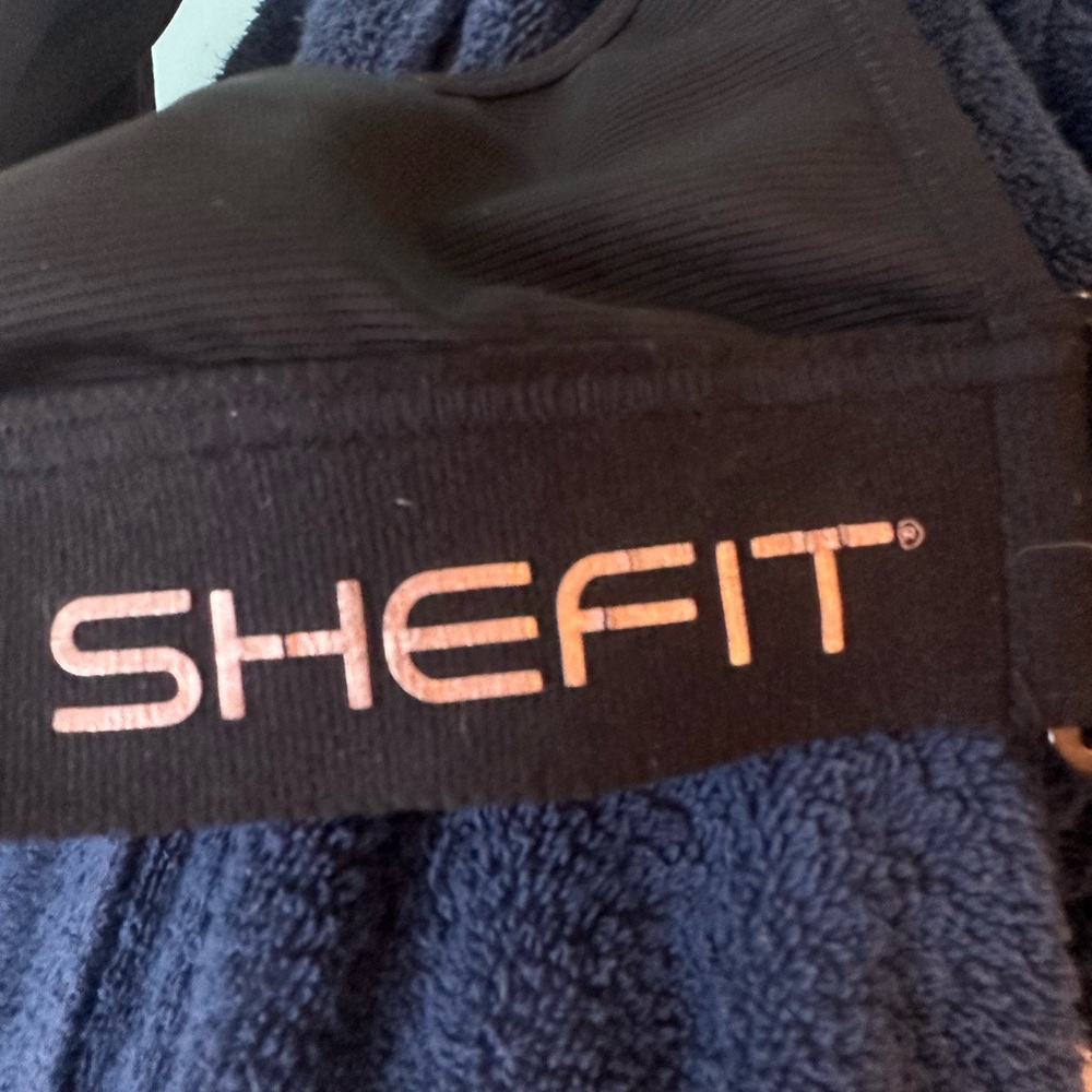 Two black SHEFIT sports bras. 3 Luxe
